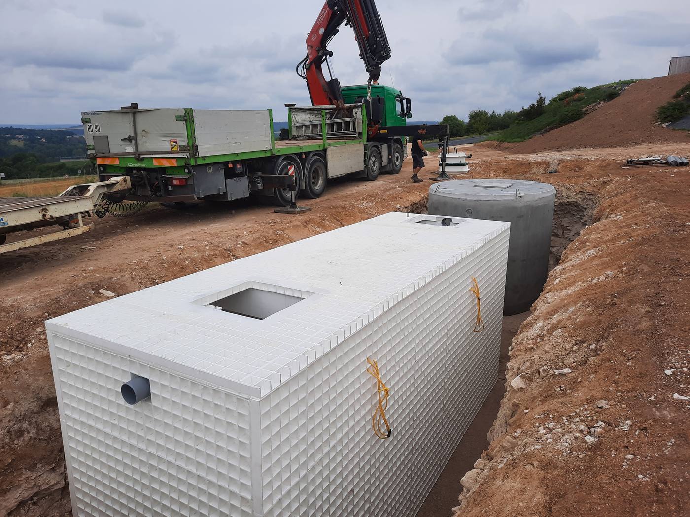 Chantier d'une station de traitement collective avec cuve fibre et regard béton